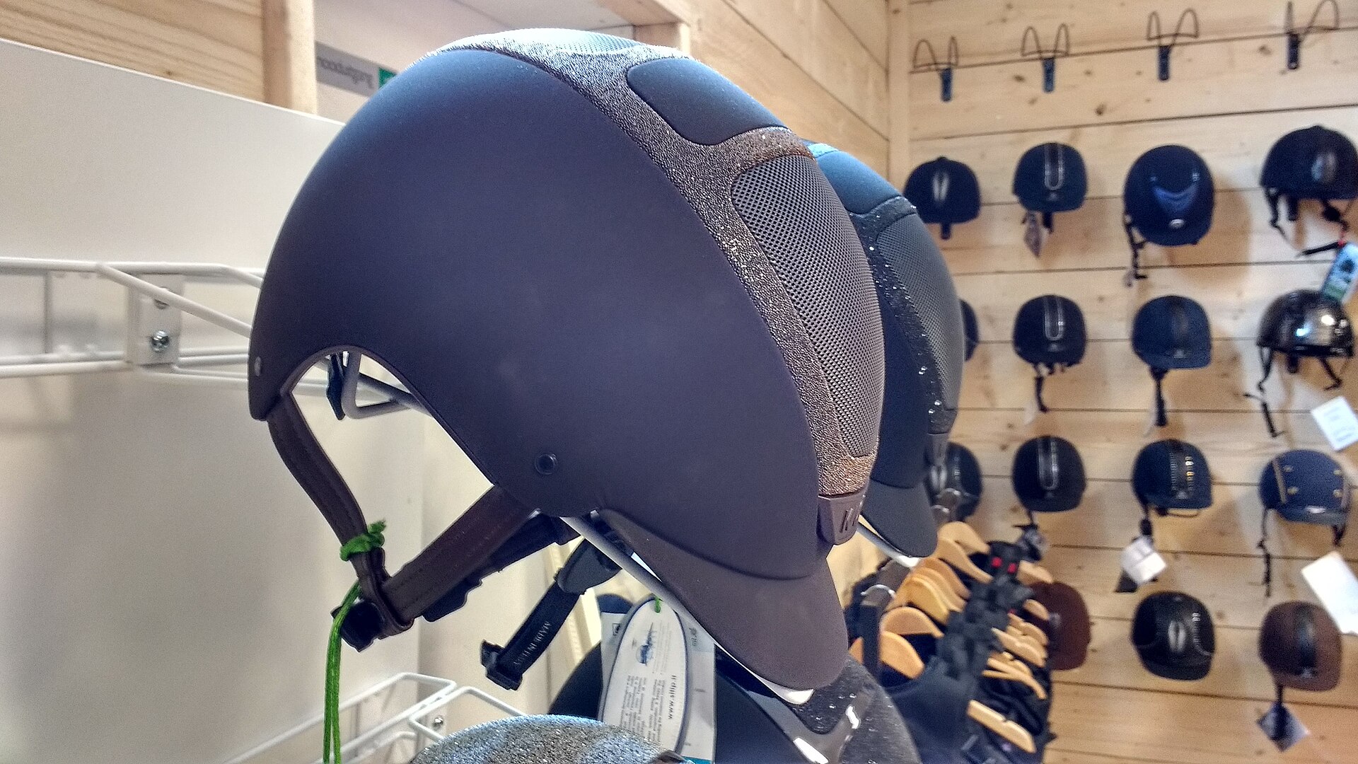 Modern riding helmets with proper chin harnesses up close on a tack-shop wall, where every good fit begins