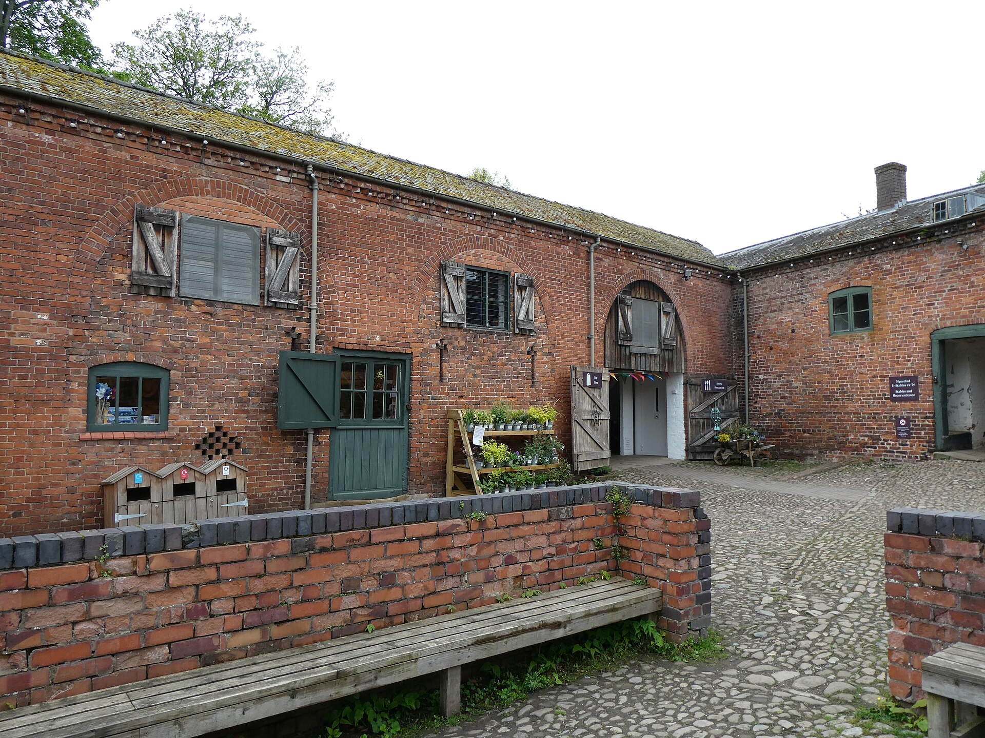 Brick stable buildings enclosing the historic stable courtyard at Erddig, their wide doorways opening onto the yard