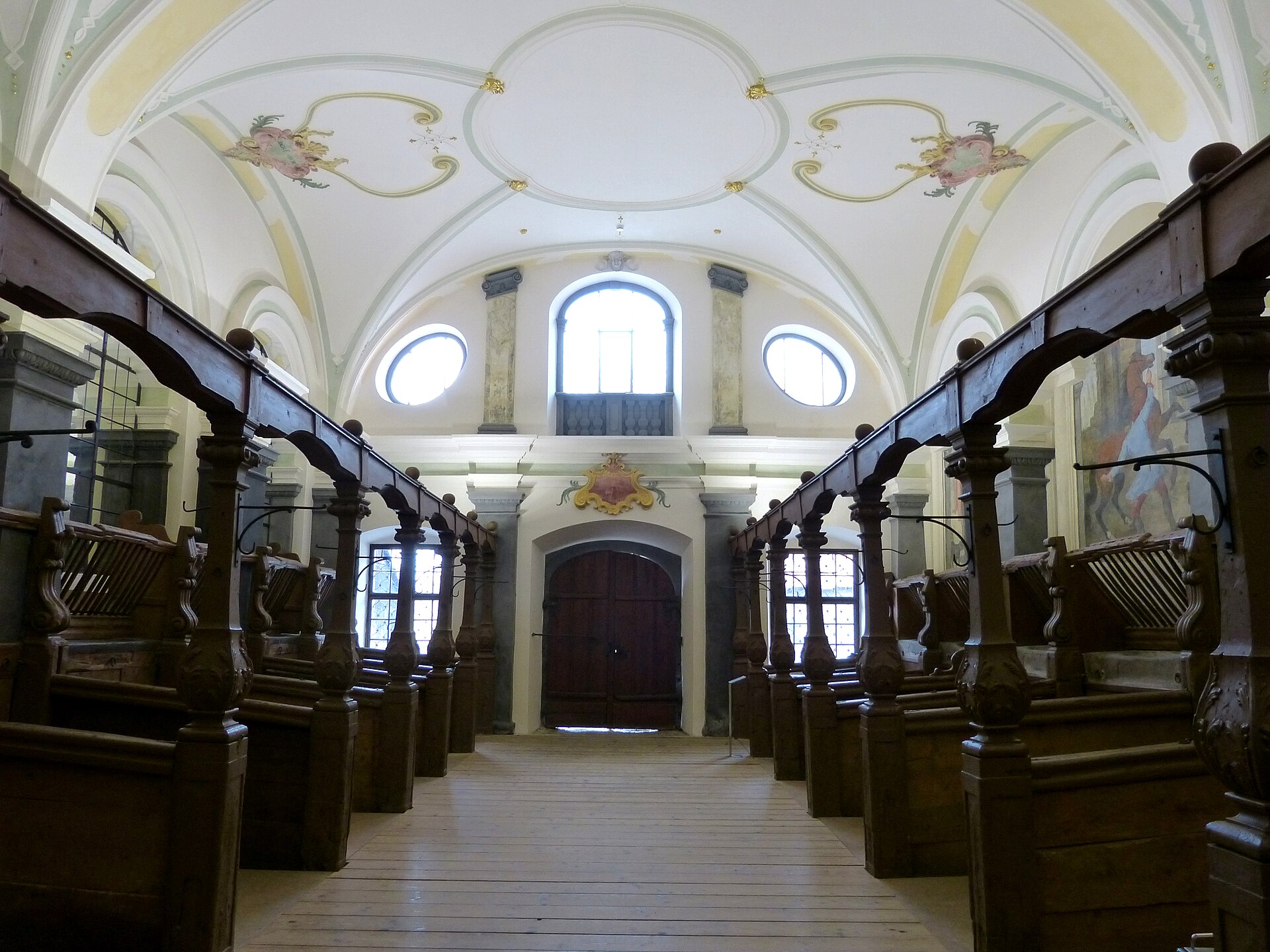 Carved oak stalls flank the centre aisle of Salem's baroque stable hall beneath a frescoed vault