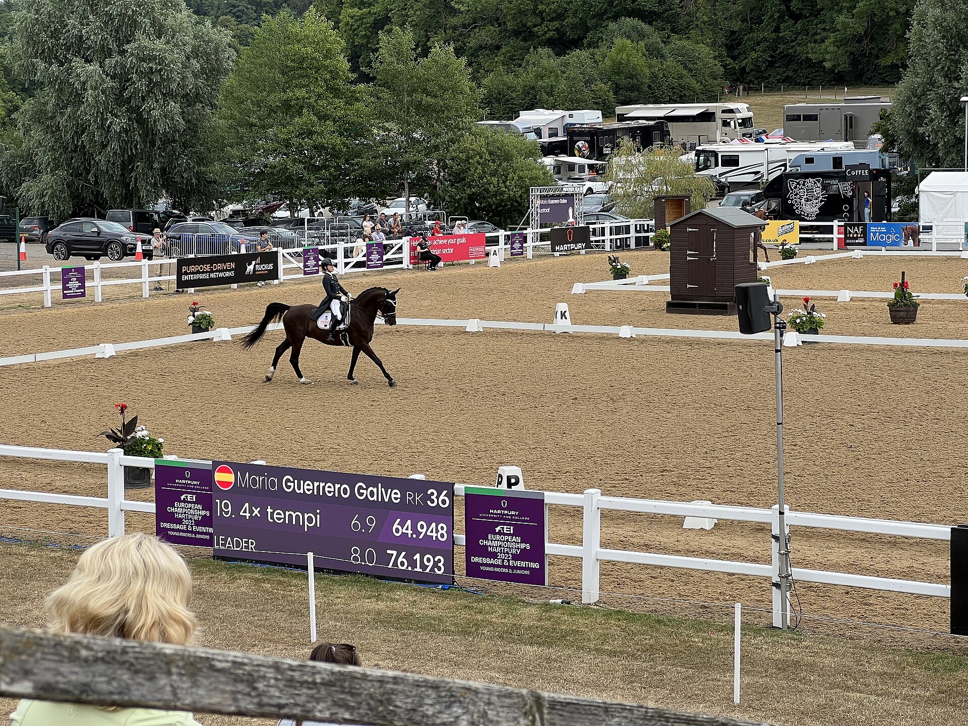 Young rider in tails trots down the long side of the competition arena at the European Young Riders dressage championships