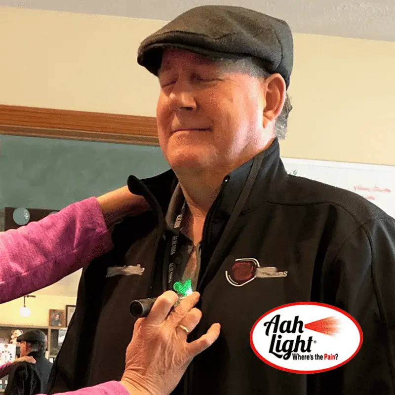 AAH Light green therapeutic torch being applied to a person's shoulder during a calming light session