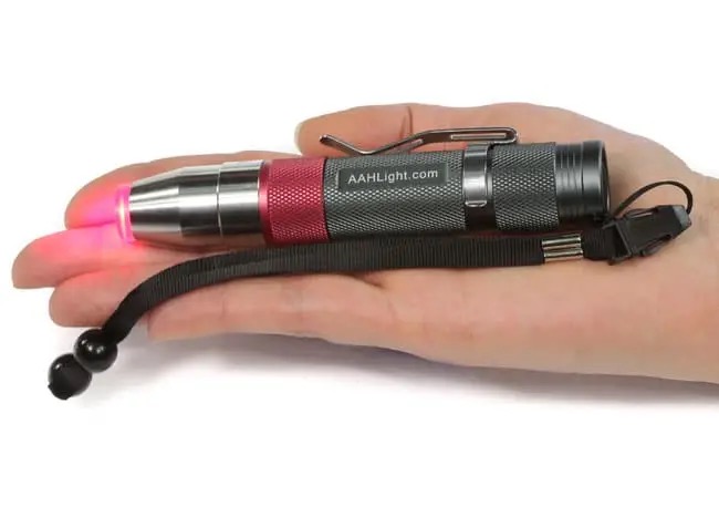 AAH Light handheld red light therapy torch held in a palm with the red emitter glowing