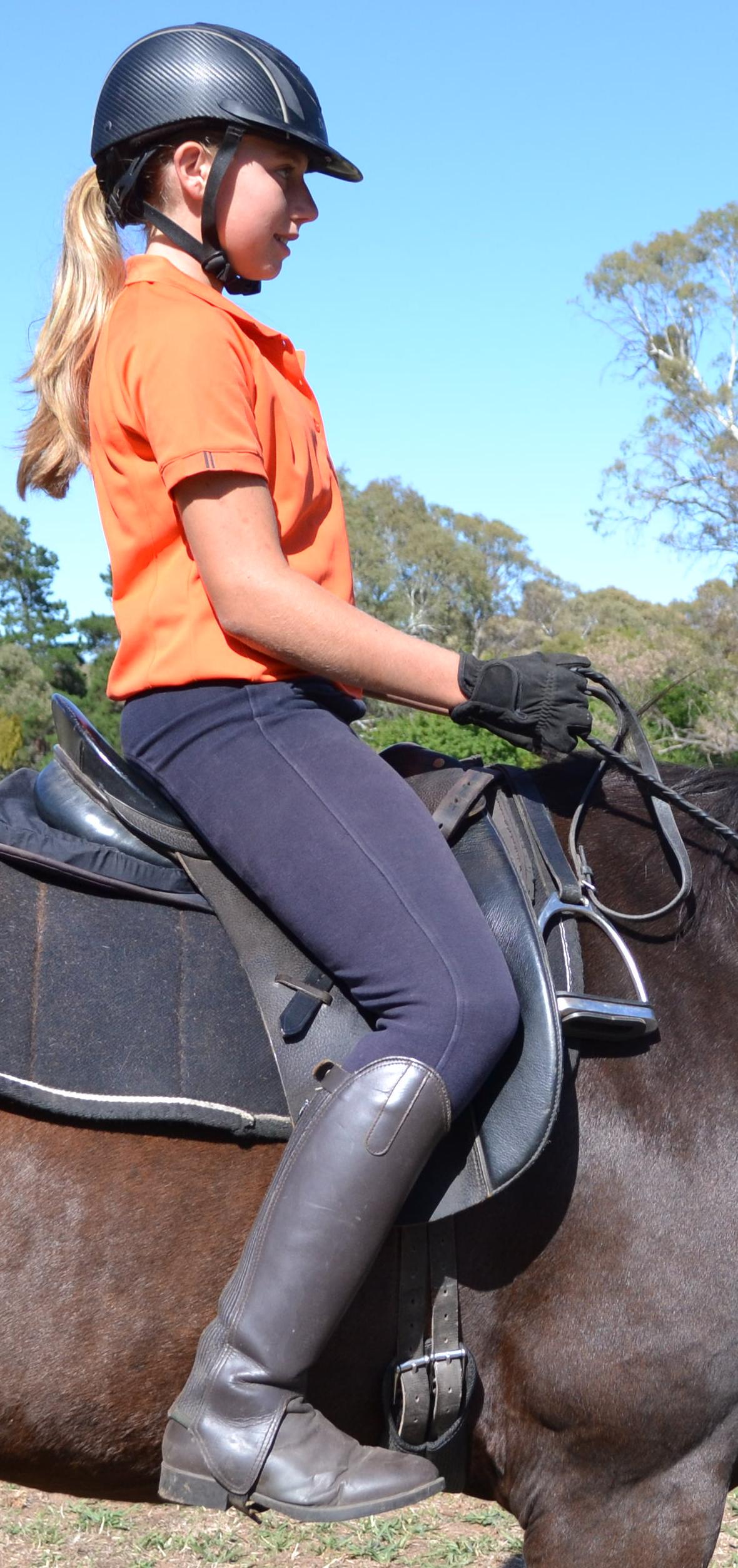 Close view of a rider's correct upright seat and leg position demonstrating Applied Posture Riding biomechanics