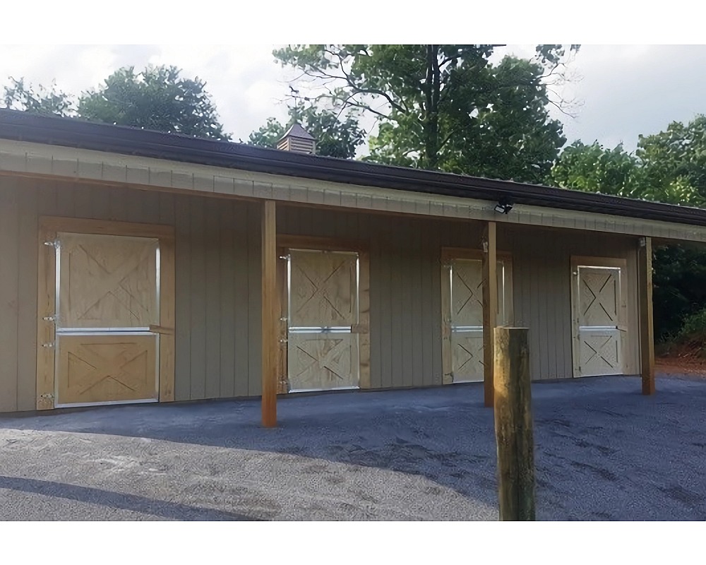 Exterior run of Armour aluminum-framed wood Dutch barn doors with X-brace styling under a covered overhang