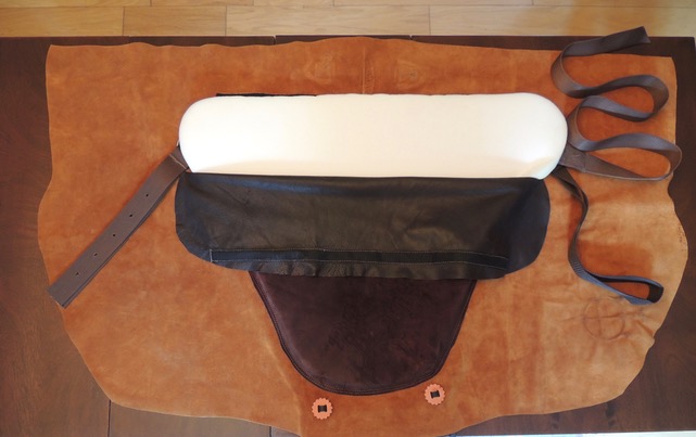 Detail of the El Compañero Bareback Rider pad showing the foam insert pocket, dark leather seat, and Western girth strap on the suede skin