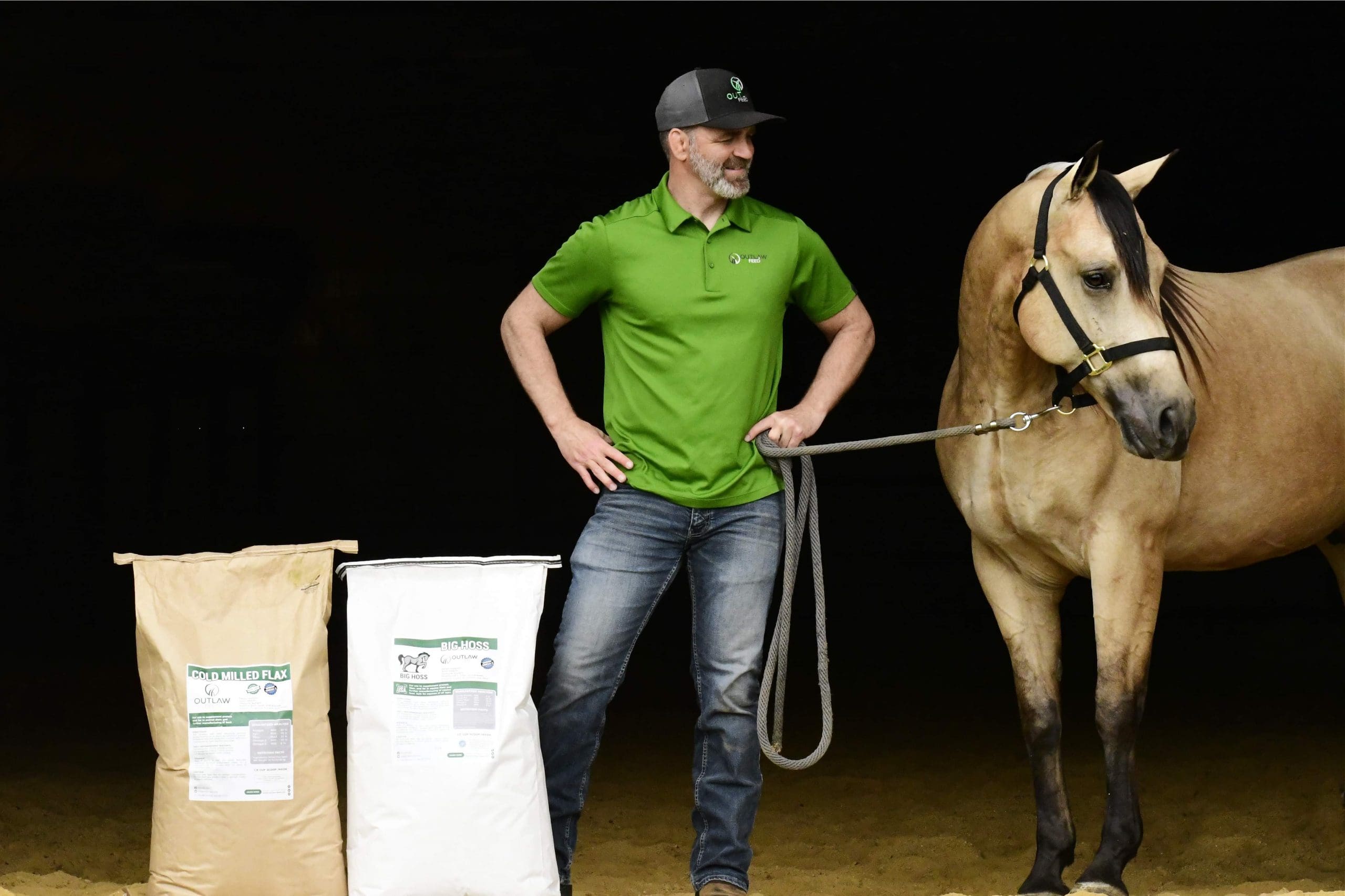 Outlaw Nutrition founder with a buckskin horse beside Cold Milled Flax and Big Hoss feed bags