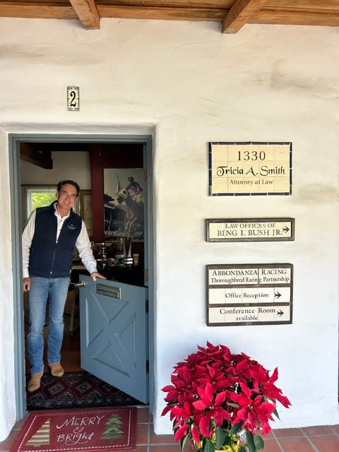Bing Bush at the door of his Del Mar law office beneath signs for the Law Offices of Bing I. Bush Jr. and Abbondanza Racing