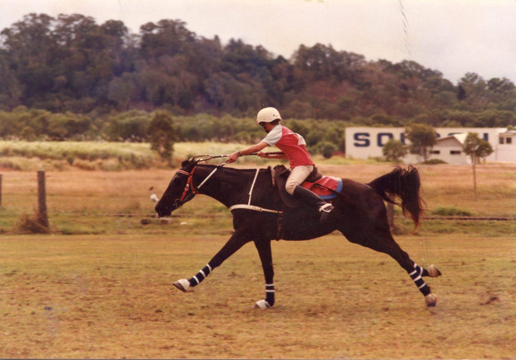 A young Clinton Anderson racing a black horse in polocrosse in Australia, the early competition roots behind the Downunder Horsemanship Method
