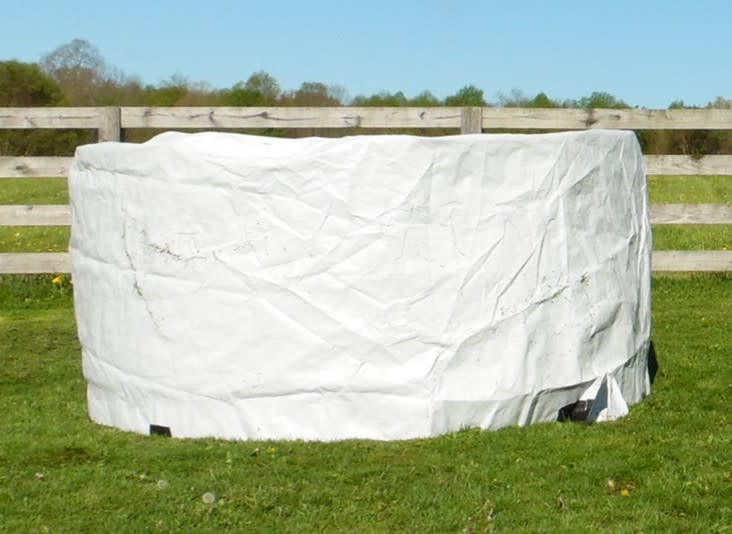 Country Acres welded-seam round hay bale cover fitted over a round bale outdoors