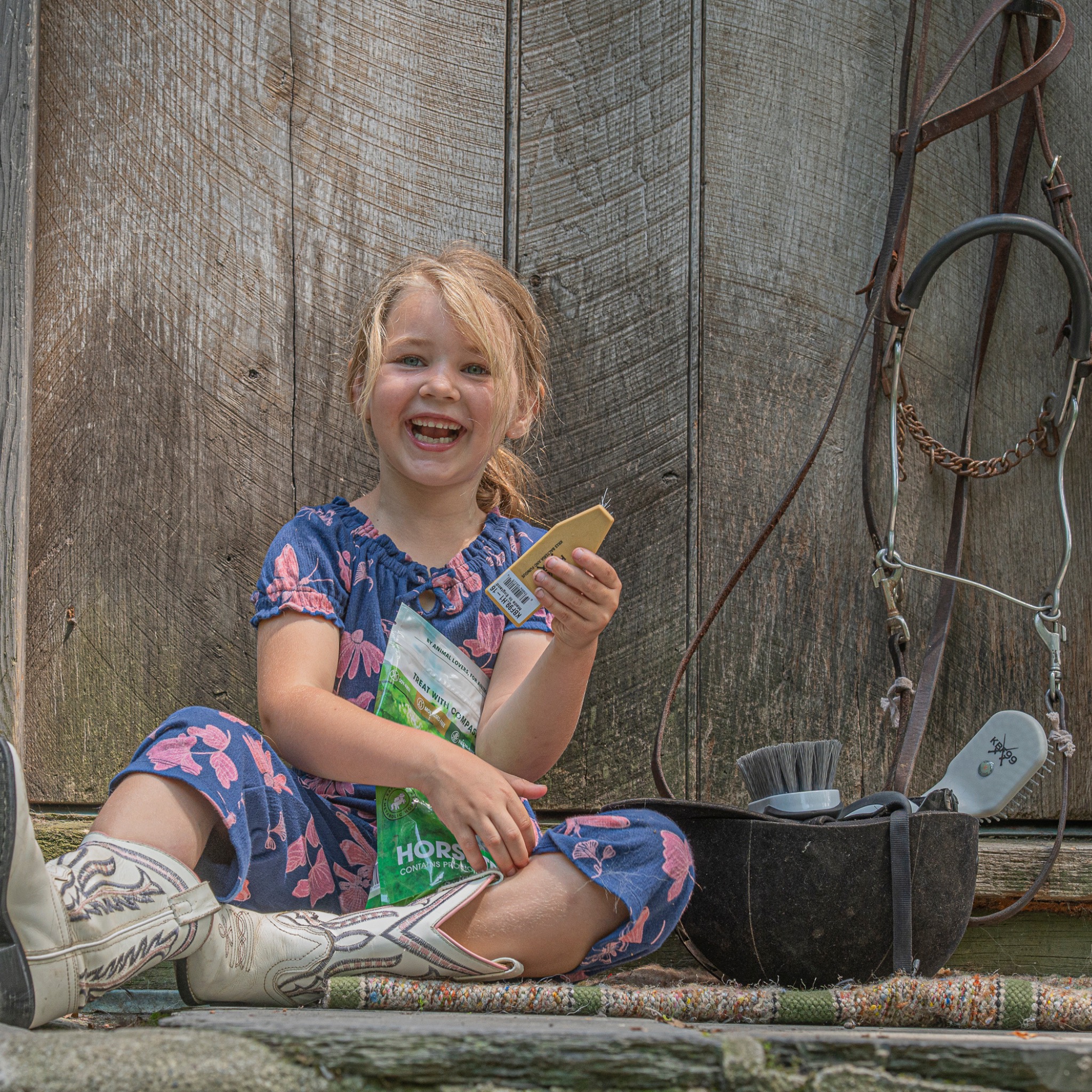 Smiling child seated by a tack wall holding a KBF99 bonding grooming brush