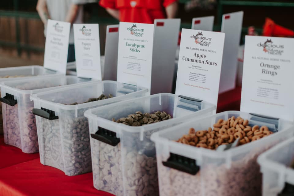 Bins of different Delicious Horse Treats flavors displayed at an event table