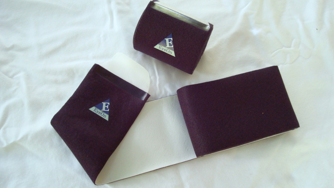 Three EyeOn far infrared therapeutic wraps with the EyeOn emblem laid open to show the soft inner lining