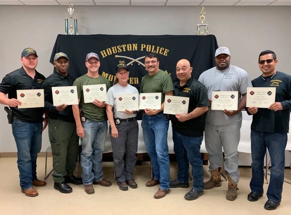 A class of first aid students holding their certificates of completion after finishing an equine first aid course
