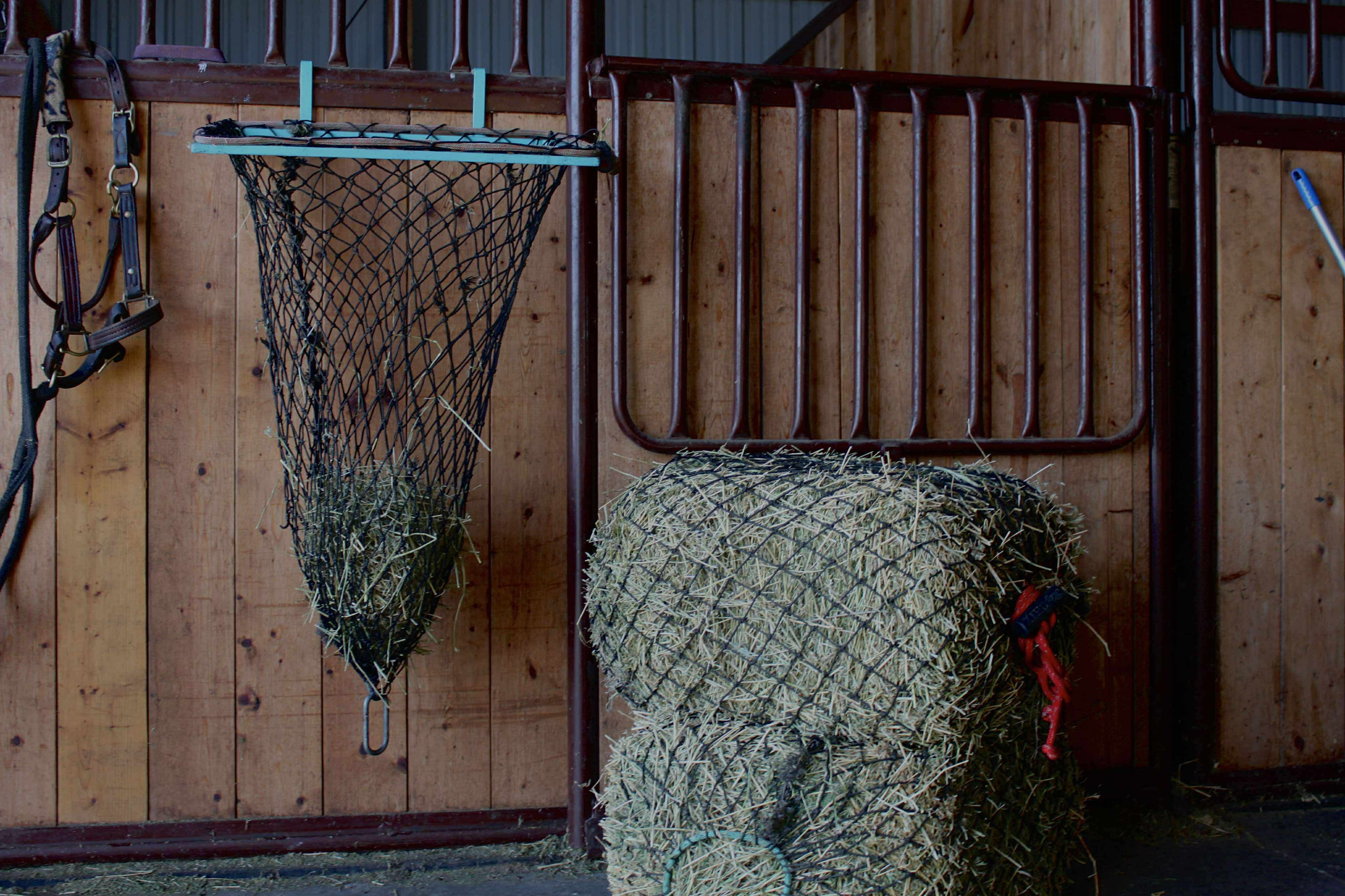 Hay-EZ hay net filler stand holding a net open for hands-free filling in the barn