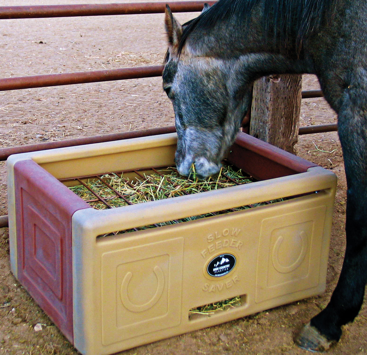 Horse grazing naturally from a High Country Plastics Slow Feeder Saver in a stall