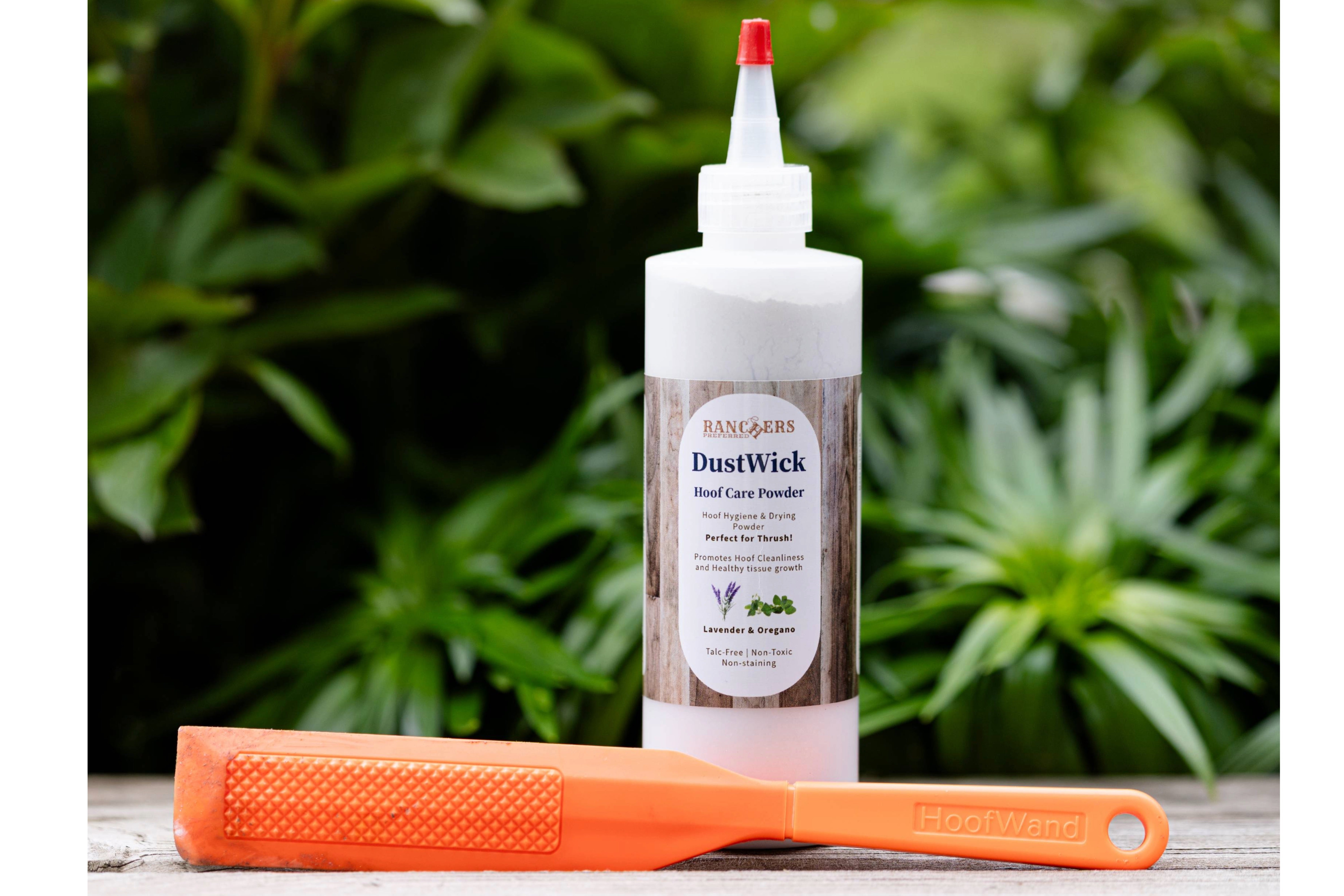 The orange HoofWand tool showing its textured cleaning surface, displayed on a green leafy background