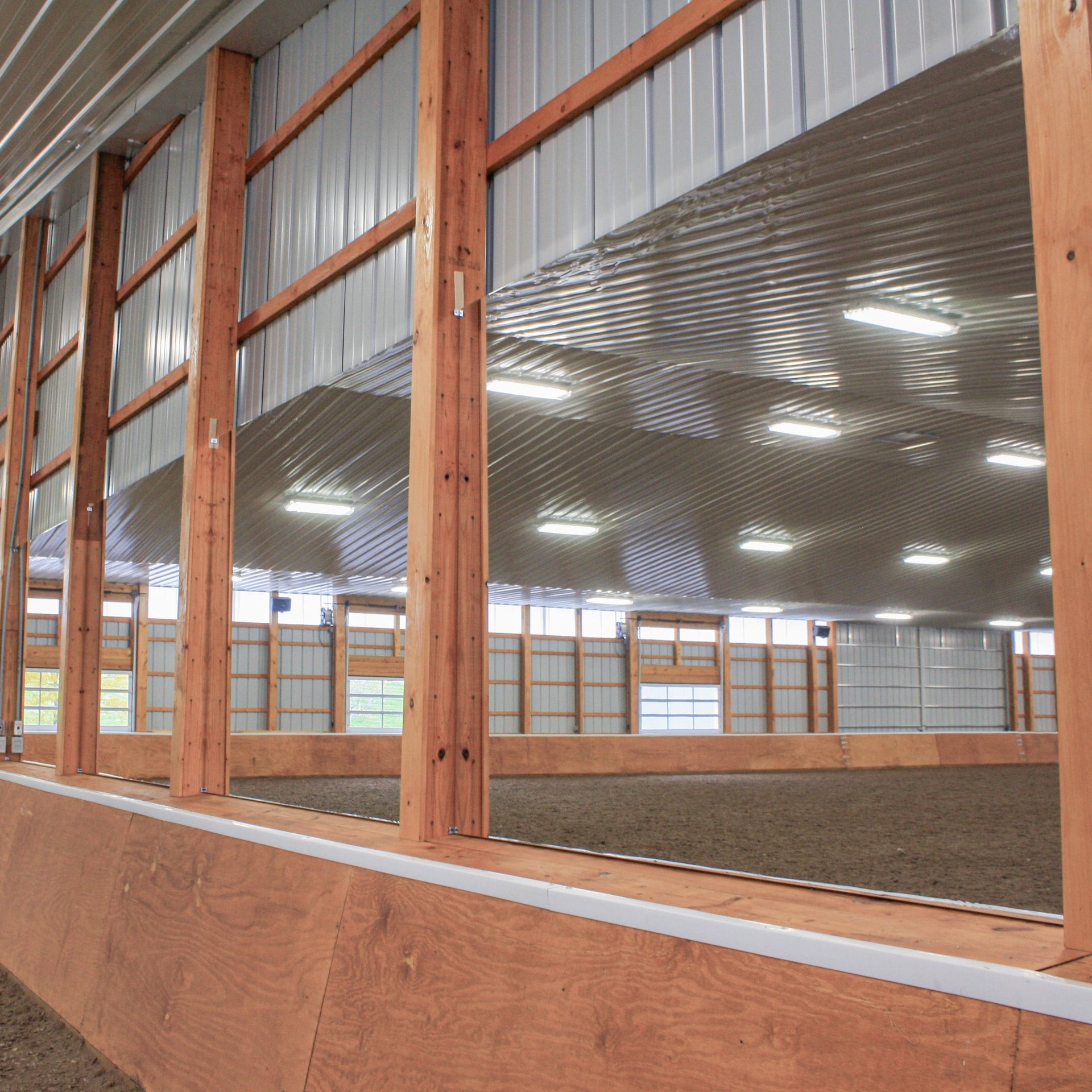 Wall-mounted LiteMirror arena mirror panels reflecting the indoor riding arena