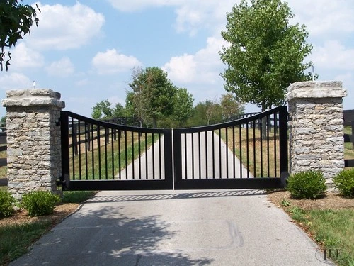 Black arched double entrance gates between stone pillars at a horse farm by Lucas Equine Equipment