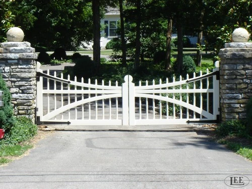 White curved double entrance gates with vertical pickets between stacked stone pillars by Lucas Equine Equipment