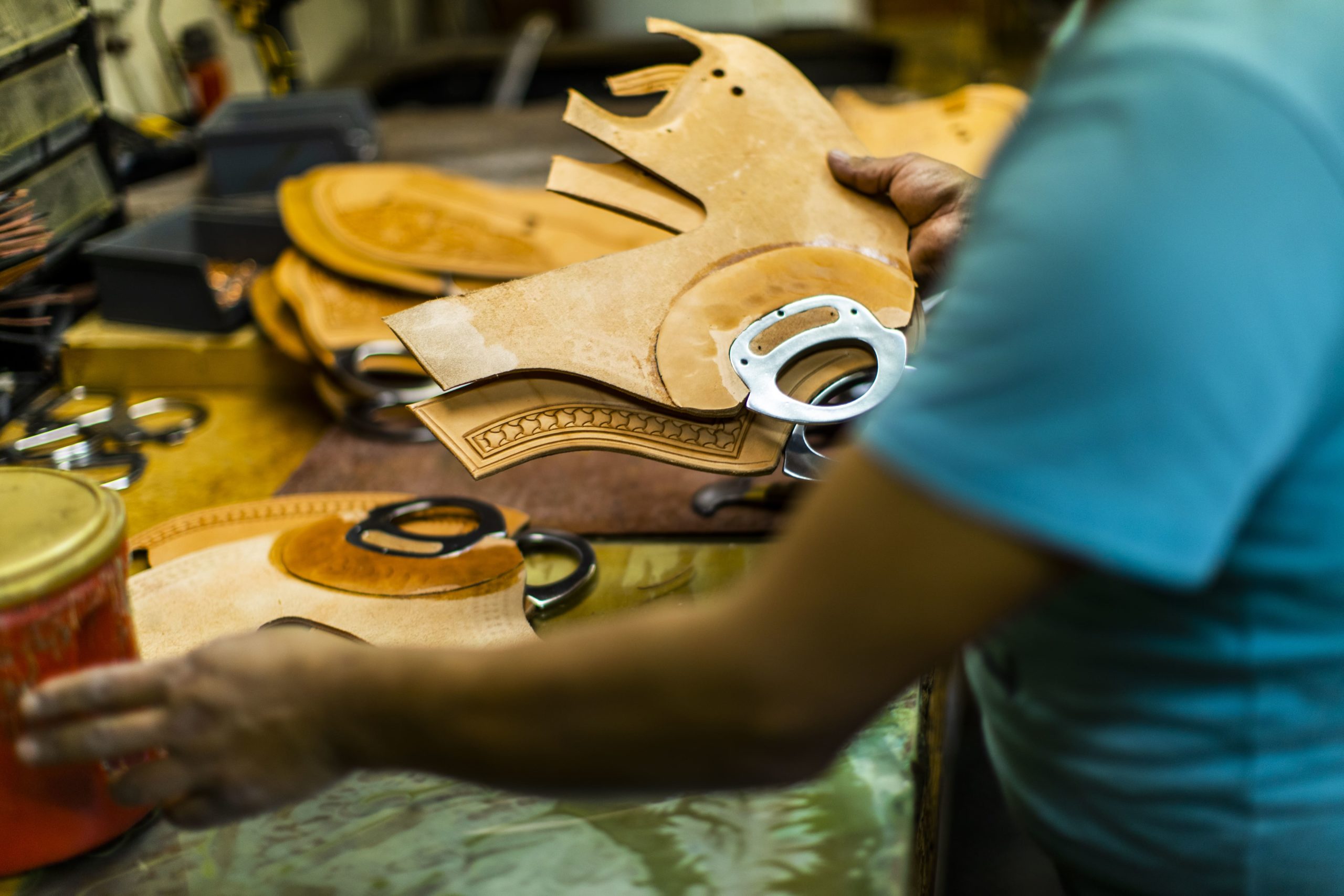 A McCall craftsman cutting and shaping heavy saddle leather by hand at the workbench