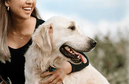 Pet owner hugging a happy healthy dog cared for with Natural Wonder Pets natural remedies