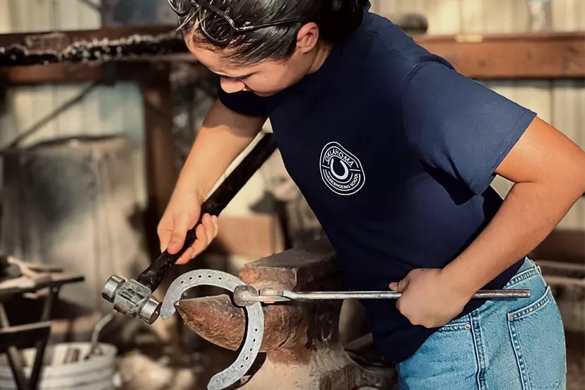Oklahoma Horseshoeing School student shaping a horseshoe on the anvil