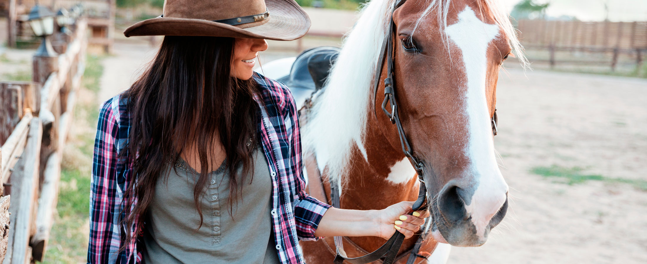 Cowgirl in a plaid shirt with her horse, illustrating chemical-free natural fly control from The Organic Cowboy