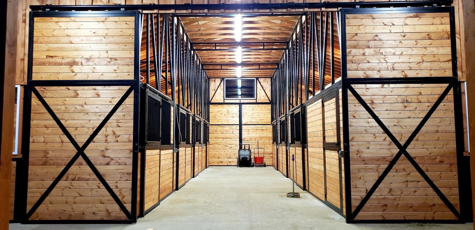 A Selkirk barn aisle lined with stall fronts and X-brace sliding doors