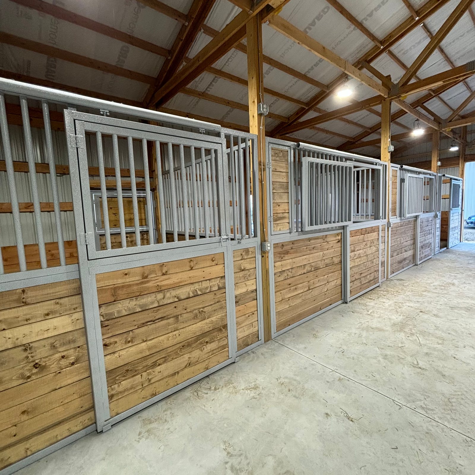 A long run of galvanized Selkirk stall fronts in a large horse barn