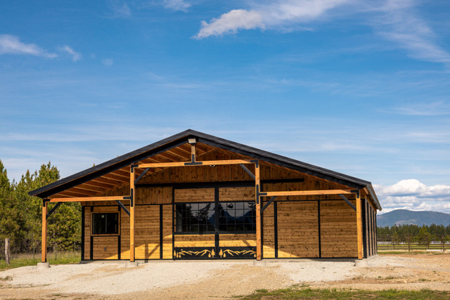 End of a Selkirk barn with the sliding X-brace doors rolled open, showing the stall aisle inside