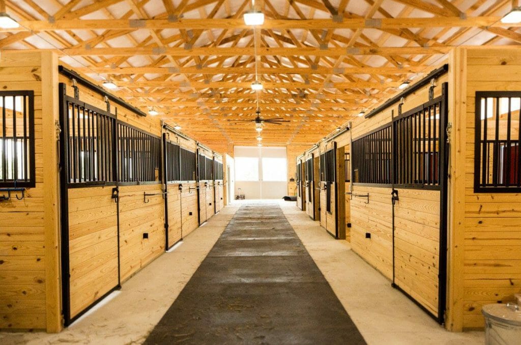 StallWorks powder-coated stall system with vertical grill bars inside an equine barn aisle