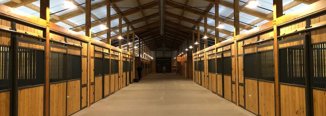 Sunset Valley Metal Craft custom horse stalls lining both sides of a finished barn aisle