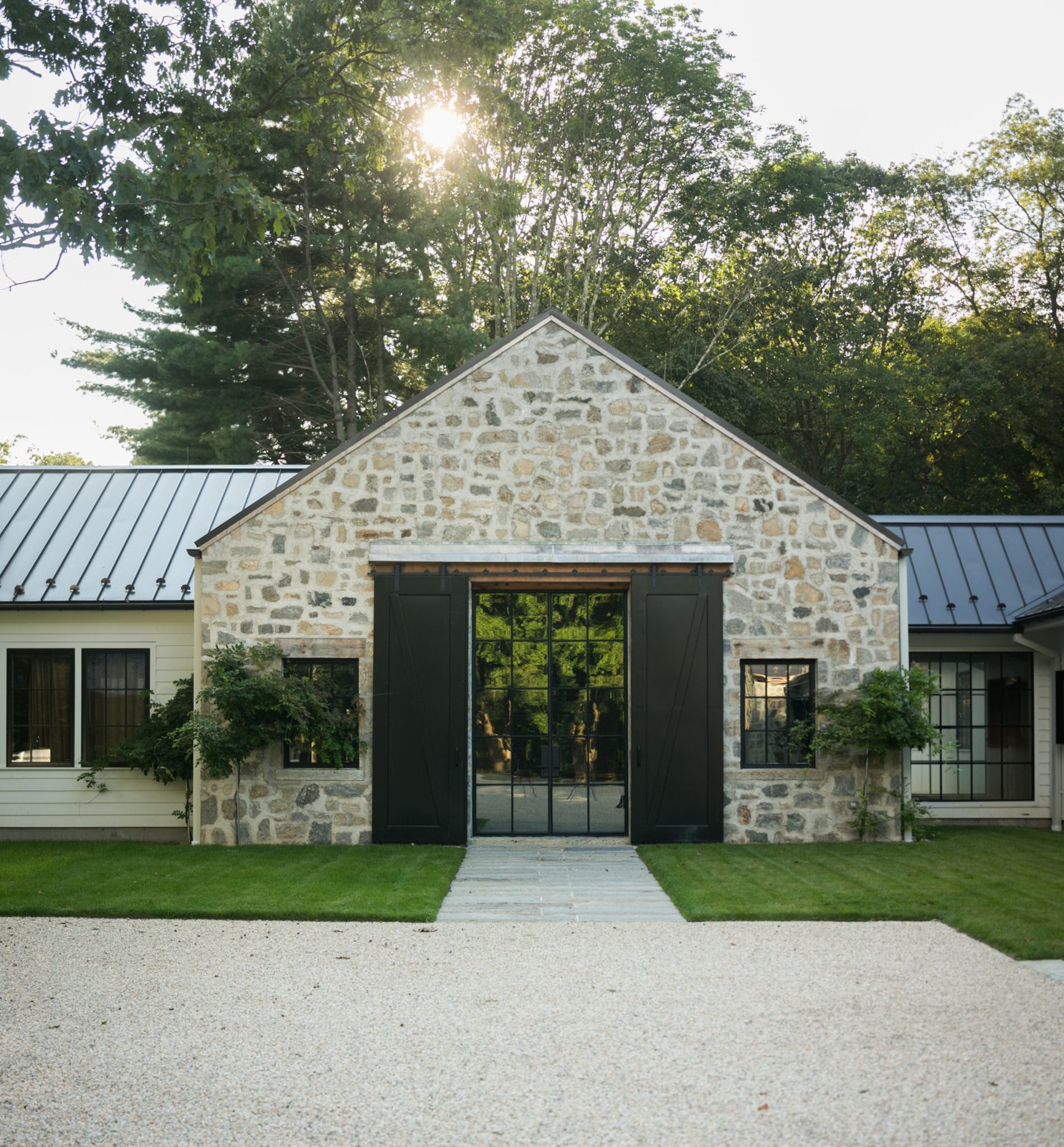 A stone horse barn fitted with black sliding aluminum barn doors by Sunset Valley Metalcraft