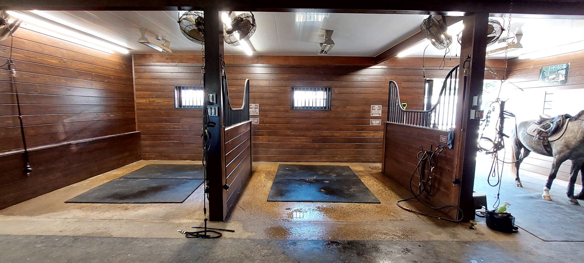 Timber-lined wash bay with cross-ties and overhead fans, part of a Sunset Valley Metalcraft barn interior renovation