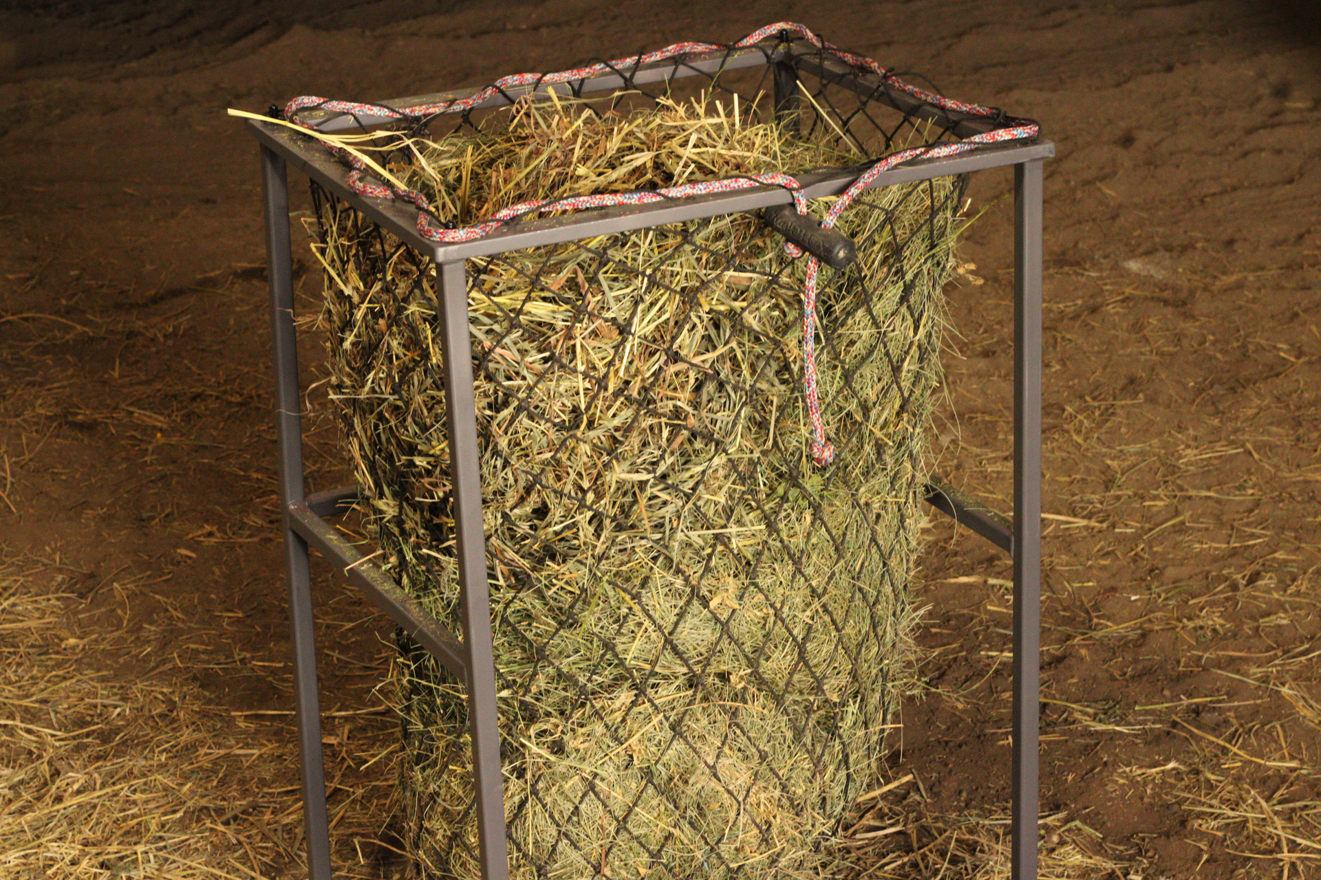 Free Standing Hay-EZ stand holding a hay net packed tightly with hay in a barn